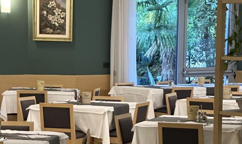 Sala da pranzo elegante e luminosa, con tavoli apparecchiati e vista sul giardino.